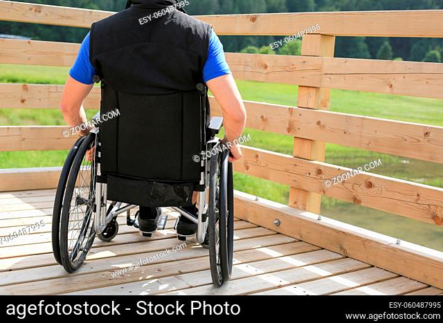 Disabled young man on a wheelchair holding and turning wheels with hand