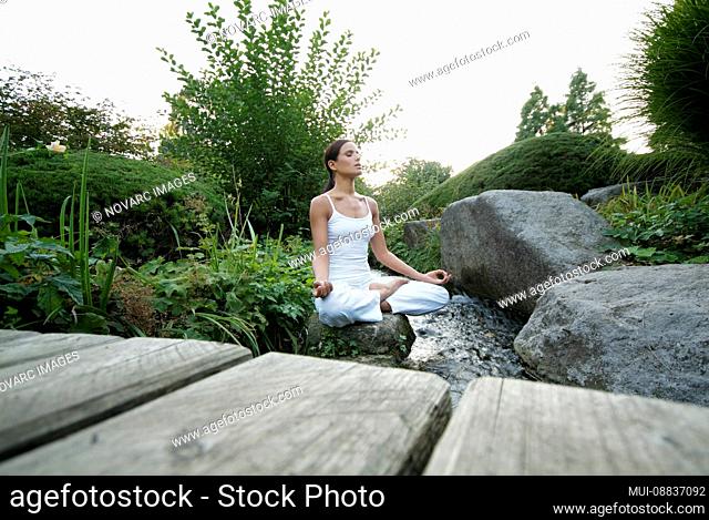 Woman is doing yoga in a garden