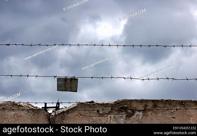 gloomy barbed wire on dark fence and grey sky