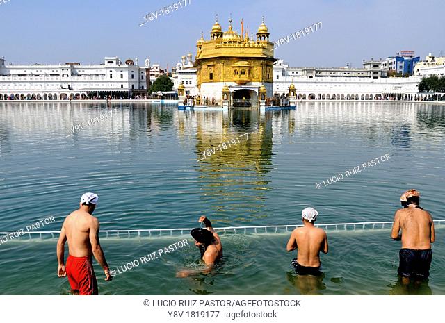 India. Punjab. Amritsar. The Golden Temple. Believers Sikh in front of the sacred pool Anrit Sarovar and the Sri Harmandir Sahib the holy of holies of Sikhism