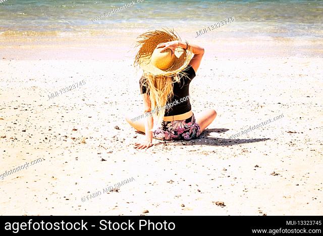 Tourism and girl alone viewed from back on vacation on summer golden beach - caucasian young female people enjoy sand and tropical resort holidays