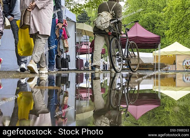 Riga, Latvia, People walking and reflected in a rain puddle at an outdoor market