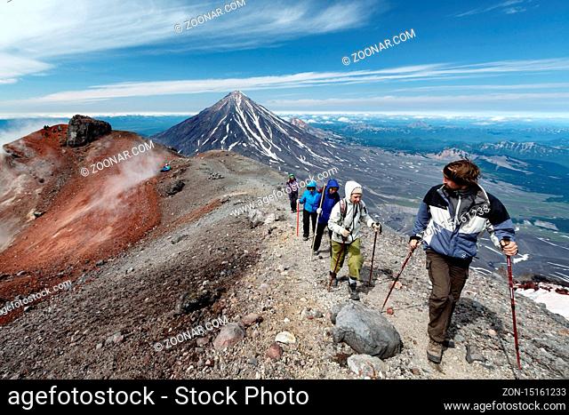 AVACHA VOLCANO, KAMCHATKA PENINSULA, RUSSIAN FAR EAST - AUG 7, 2014: Group of hikers climbing along the edge of summit crater of active Avachinsky Volcano on...