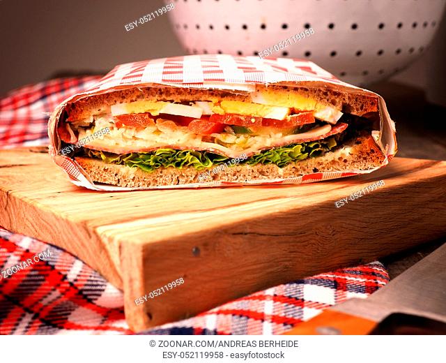 Tasty homemade sandwich with organic ingredients like eggs, tomatoes, salami, cheese and fresh lettuce