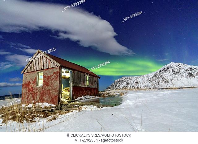 Northern Lights over an abandoned log cabin surrounded by snow and ice. Flakstad. Lofoten Islands Northern Norway Europe
