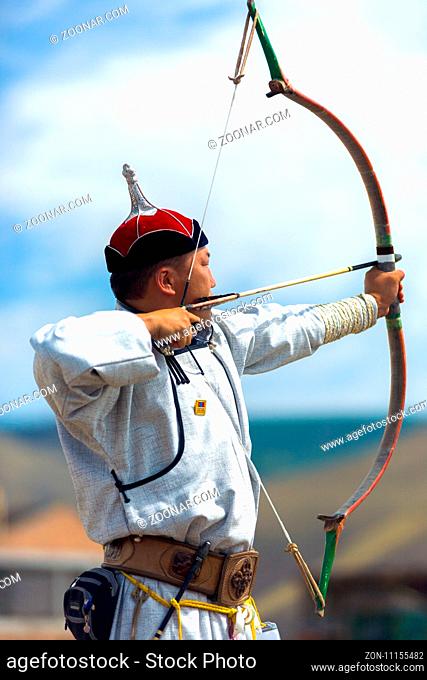 Ulaanbaatar, Mongolia - June 11, 2007: Male archer in traditional garb pulling bowstring and aiming arrow with concentration at the Naadam Festival archery...