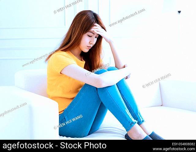 sad young woman sitting on sofa at home