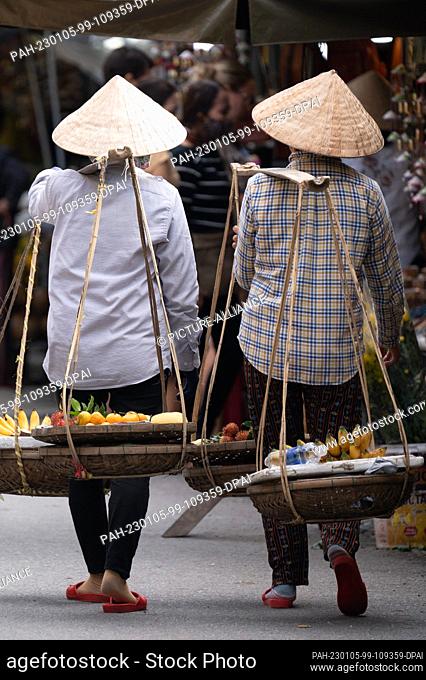 22 November 2022, Vietnam, Hoi An: Two women with cone hats carry baskets with fruit. Photo: Sebastian Kahnert/dpa. - Hoi An/Quang Nam/Vietnam