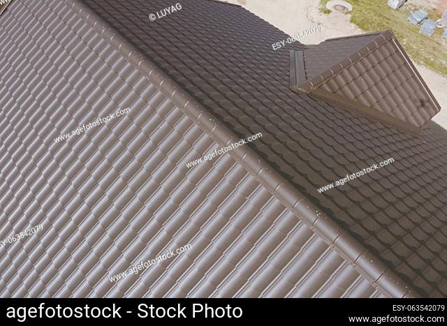 Modern roof made of metal. Brown metal tile on the roof of the house. Corrugated metal roof and metal roofing
