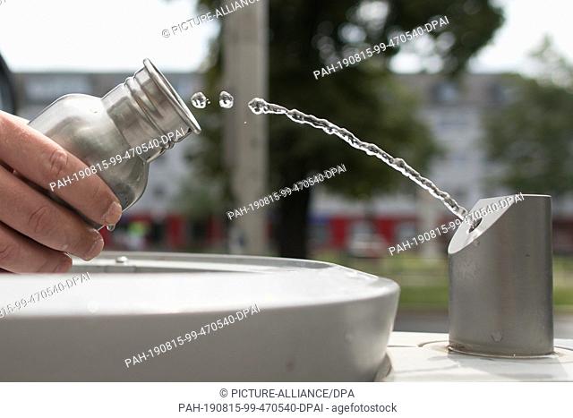 12 August 2019, Berlin: A passer-by fills his drinking bottle with water at a Berliner Wasserbetriebe fountain, a so-called ""refill station""