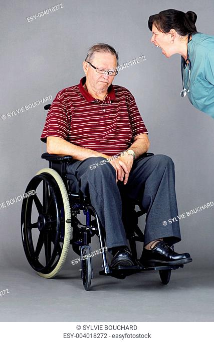 Sad senior man in wheelchair being shouted at by nurse