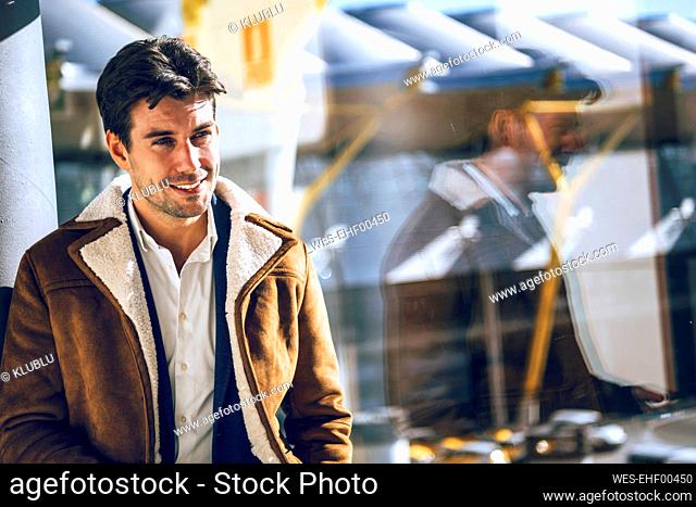 Thoughtful businessman by glass window during sunny day