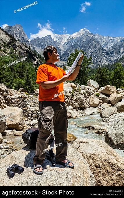 Hiker trekker studying map route on trek in Himalayas mountains. Himachal Pradesh, India, Asia