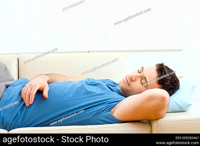 Young handsome man sleeping on couch at home, side view