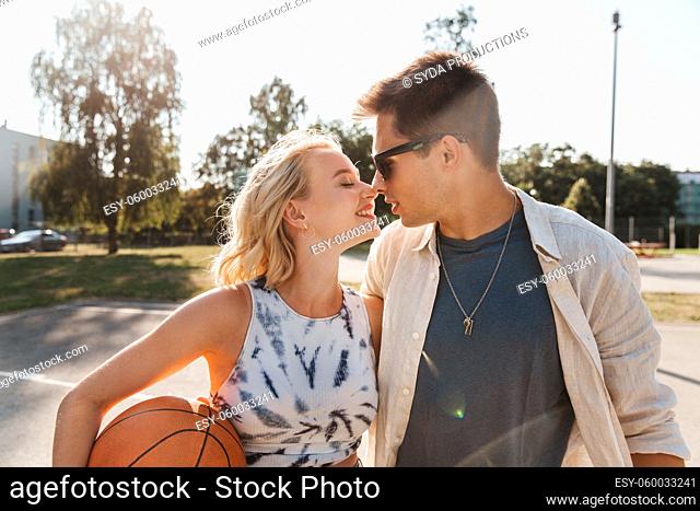 happy couple with ball on basketball playground