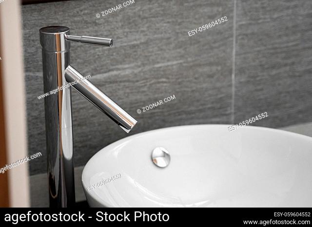 Bathroom interior with white round sink and chrome faucet in a modern bathroom