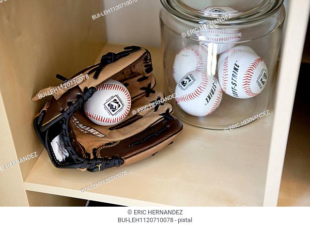 Close-up of baseball gloves with balls in jar on shelf; San Marcos; California; USA