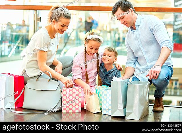 Familie und Kinder im Einkaufszentrum betrachtet die vielen Einkaufstüten