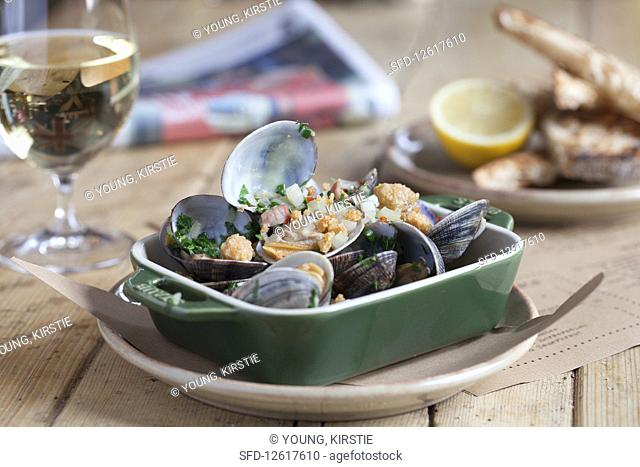 Clams with bacon and white wine sauce served with sourdough bread and white wine