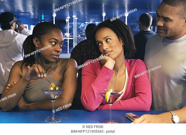 Two African women looking at each other at bar