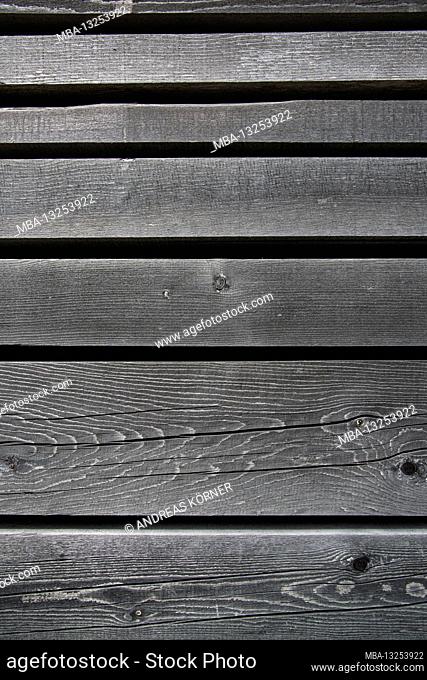 Faded, parallel wooden slats with knotholes and cracks against a black background