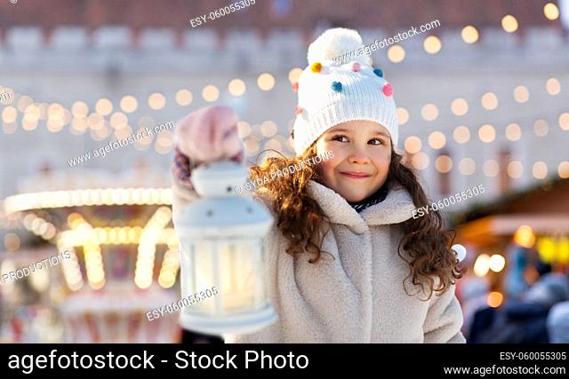 happy little girl with christmas lantern in winter