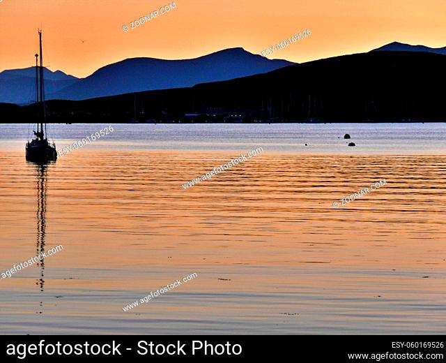 Boat silhouetted, stunning sunset and hills beyond, Oban, Scotland. Ample copy space. High quality photo
