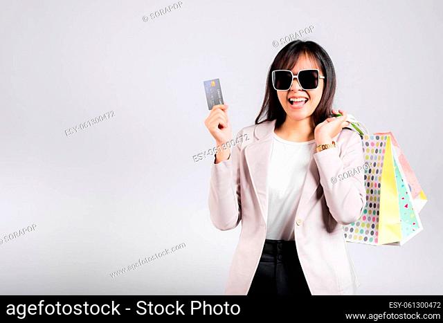 Woman with glasses confident shopper smile hold online shopping bags and credit card for payment on hand, Portrait excited happy Asian female fashion shop...