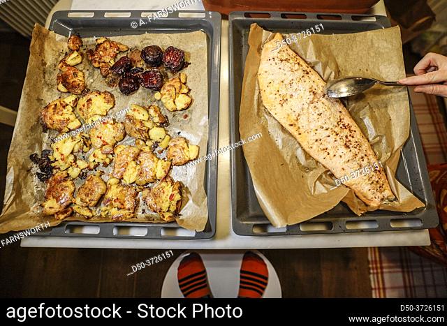 A tray of homemade seasoned oven-baked salmon and crushed potatoes side by side on a table