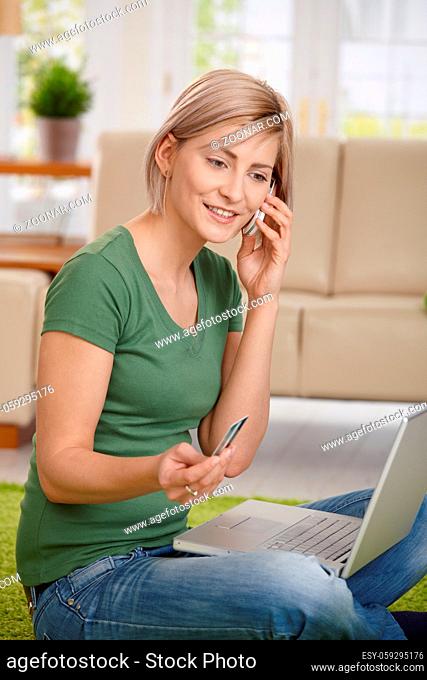 Woman paying bills from home with credit card, laptop and mobile phone