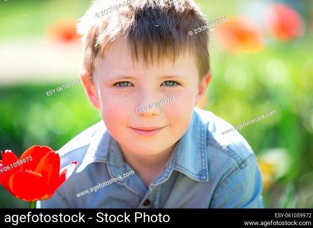 Portrait of six seven year old boy in the street with tulips