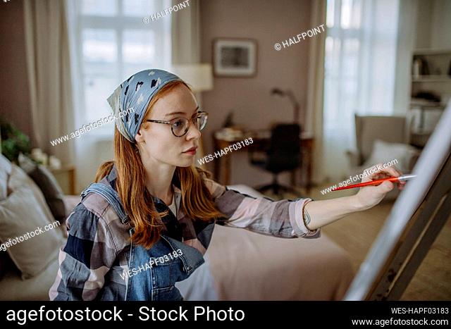 Woman wearing eyeglasses practicing painting at home