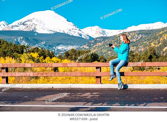 Woman tourist taking photo. Season changing from autumn to winter. Rocky Mountains, Colorado, USA