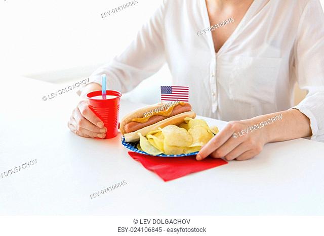 independence day, celebration, patriotism and holidays concept - close up of woman eating hot dog with american flag decoration and potato chips