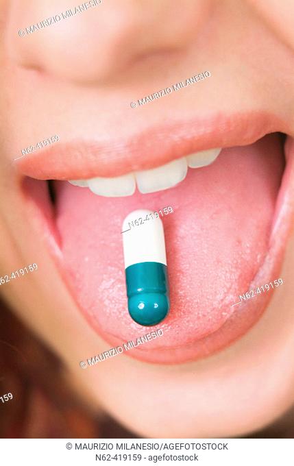Pillon green and white resting on the tongue of a girl with open mouth
