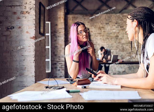 Two creative businesswomen talking in loft office