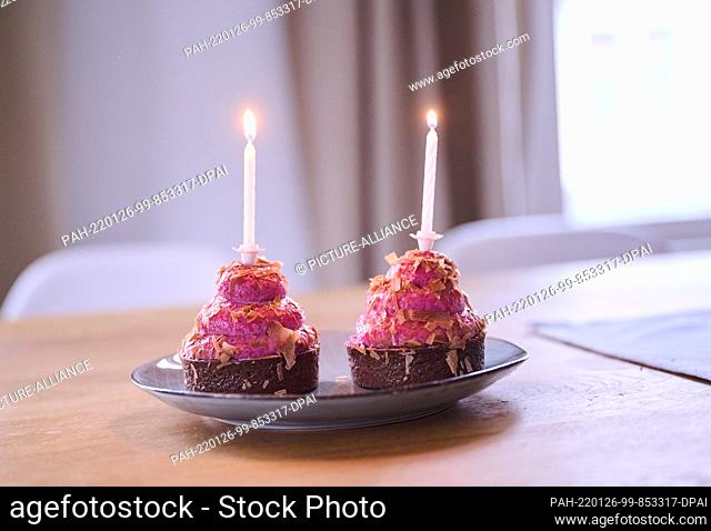 PRODUCTION - 12 January 2022, Berlin: ILLUSTRATION - Two cupcakes with burning candles are placed on a table. (posed scene) Photo: Annette Riedl/dpa