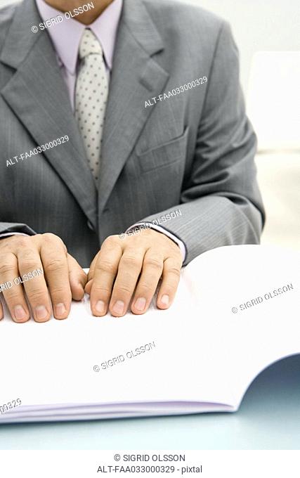 Businessman reading braille document, cropped view