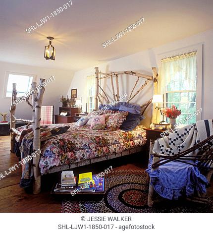 BEDROOM - Country bedroom with birch bed frame, wide plank wood floors, floral and denim bedding, valances, white walls, braided rug, books on small stool