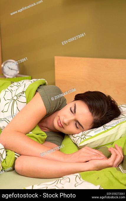 Mid-adult woman sleeping late in morning in bedroom