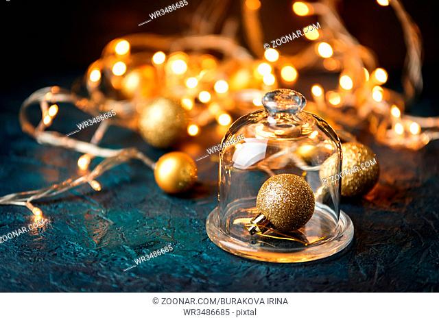Golden christmas ball under the glass cap on the background of blurred lights. Shallow depth of field