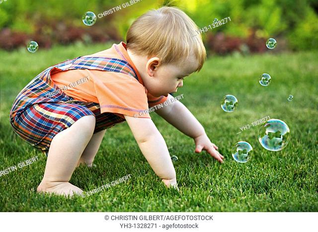 Portrait of a toddler playing with bubbles in the garden