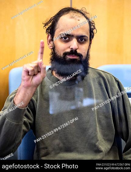 23 October 2023, North Rhine-Westphalia, Duesseldorf: The defendant Maan D. sits in the dock behind a pane of glass, showing the salute of the IS fighters
