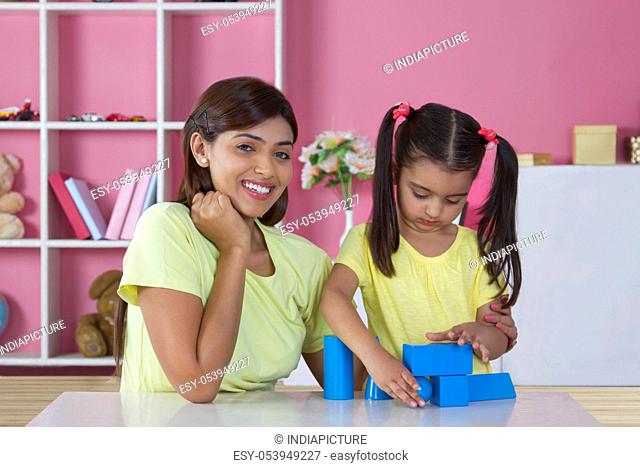 Portrait of mother with daughter playing shaping blocks at table