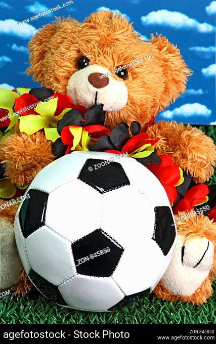 Teddybär mit Fussball mit Himmel als Hintergrund