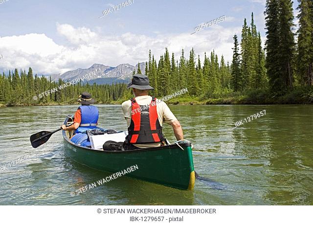 Couple, man and woman, canoeing, paddling, upper Liard River, Pelly Mountains behind, Yukon Territory, Canada