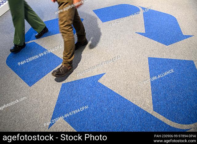06 September 2023, Saxony-Anhalt, Sülzetal: Employees of the company ""Li-Cycle"" walk across a carpet on which the recycling sign can be seen