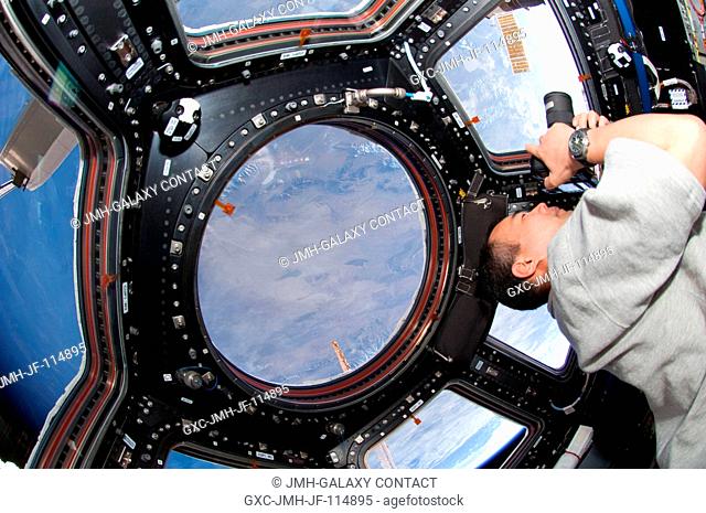 Japan Aerospace Exploration Agency (JAXA) astronaut Soichi Noguchi, Expedition 22 flight engineer, uses a still camera at a window in the Cupola of the...