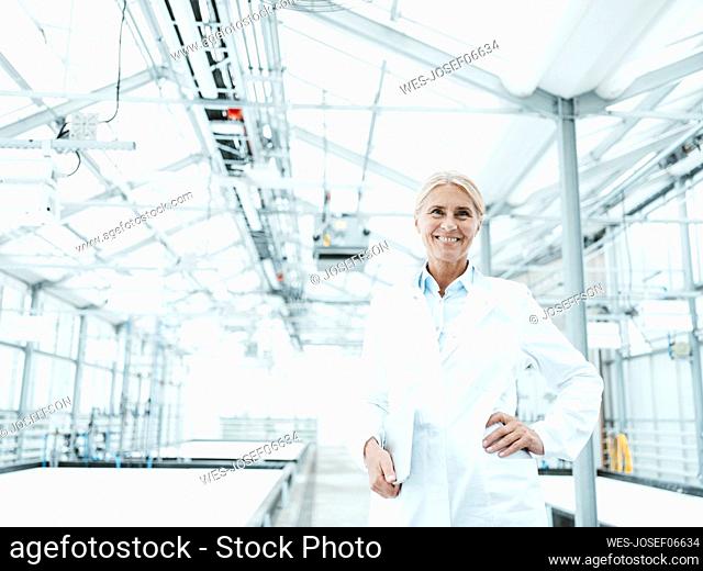 Happy scientist with hand on hip in industry