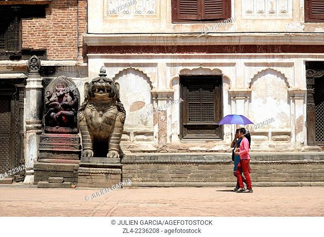 Women with umbrella and statues at Durbar Square. Nepal, Kathmandu valley, Bhaktapur
